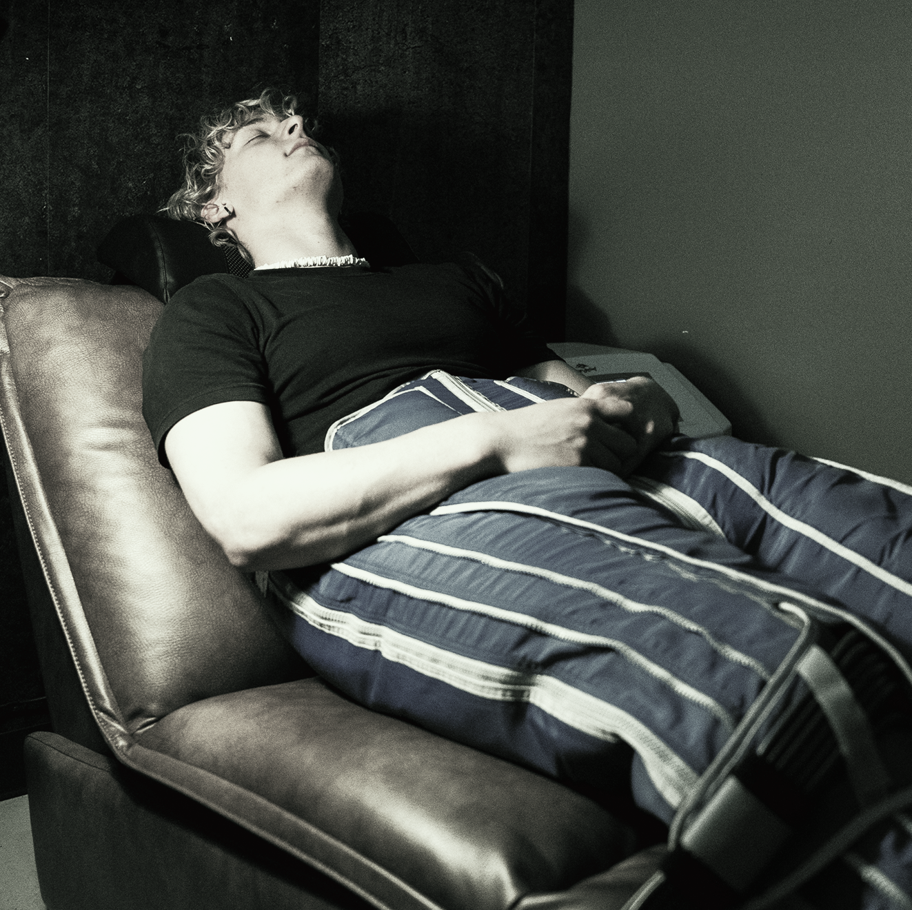 A man is laying in a chair with blue striped pants on