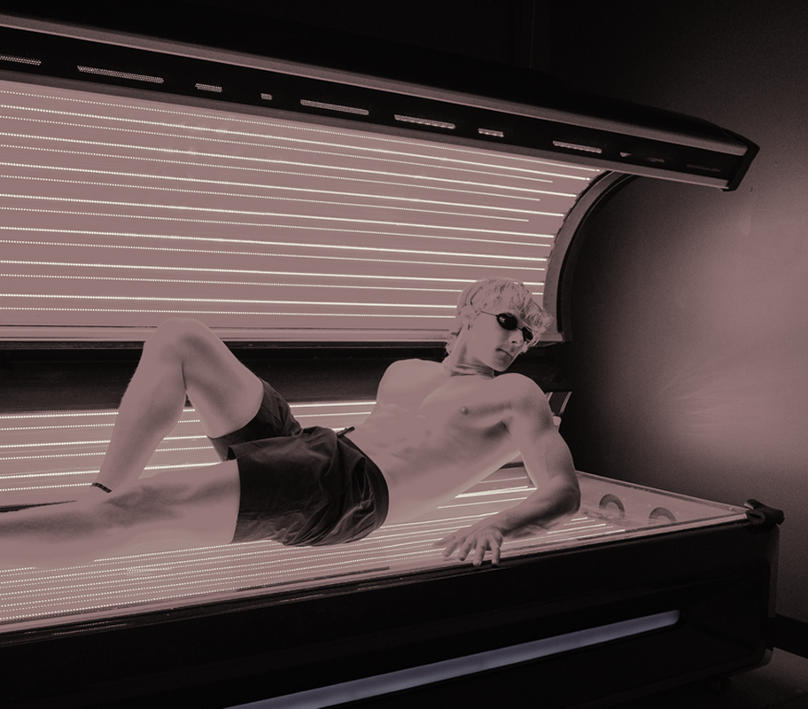 A man is laying in a tanning bed wearing sunglasses