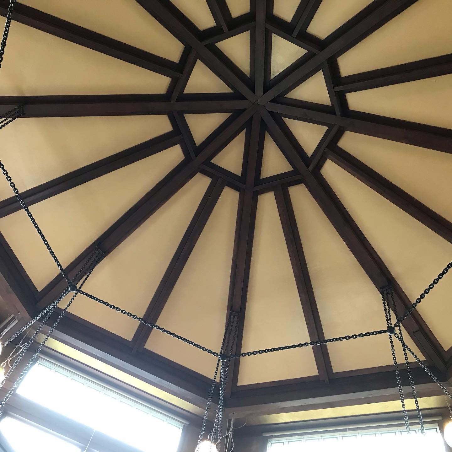 Wooden ceiling with dark beams, light panels, and hanging chains.