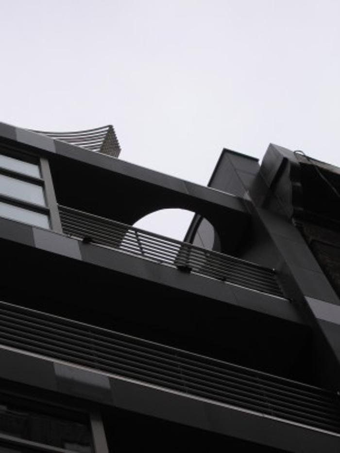 Modern gray building exterior with a rounded balcony and overcast sky.