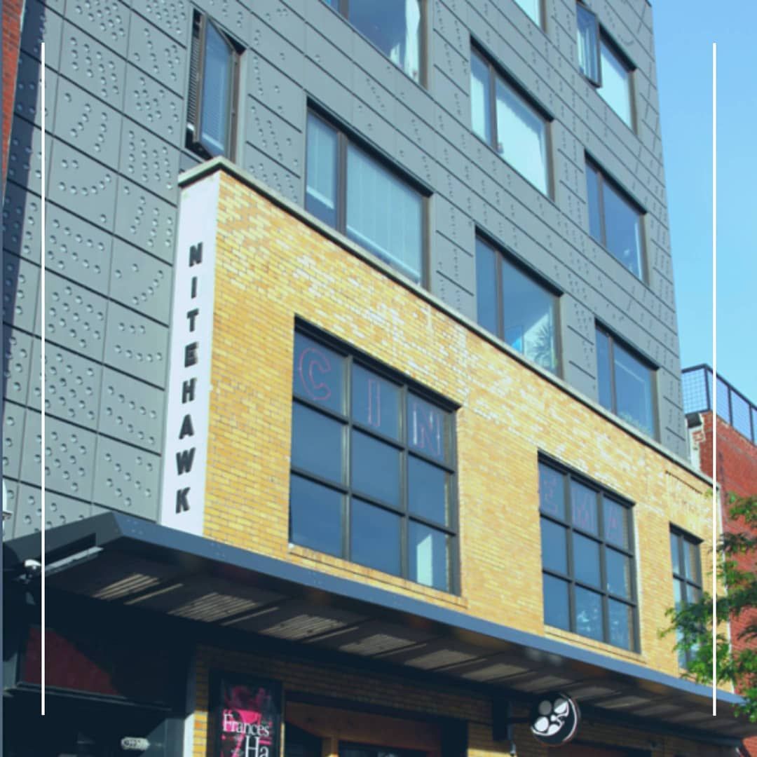 Exterior of Nitehawk Cinema building with yellow and gray facade and awning.