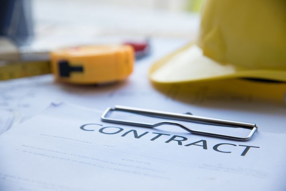 Contract on clipboard with construction tools and hard hat.
