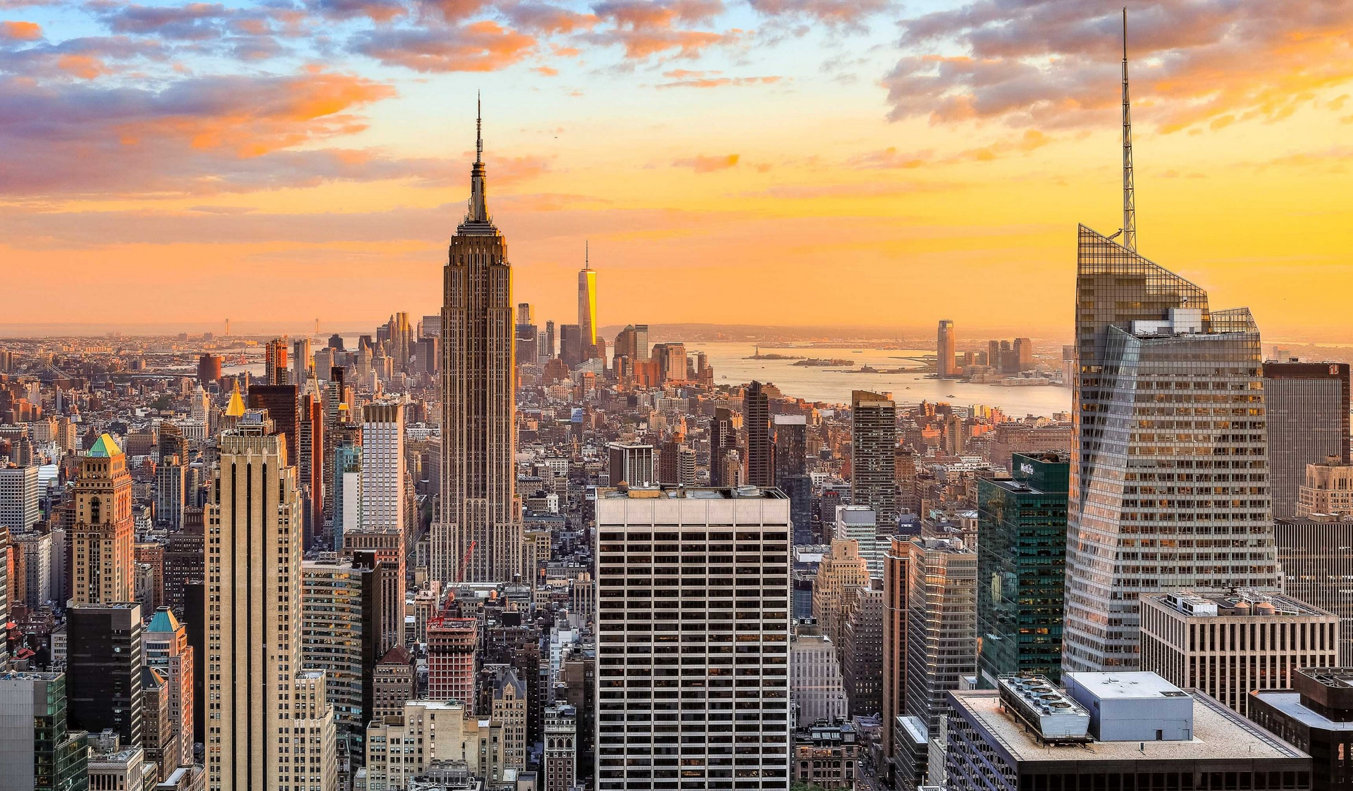 New York City skyline at sunset, with the Empire State Building prominent against a colorful sky.