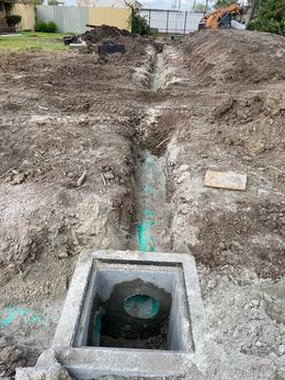 Trench excavation with a concrete utility box in the foreground at a construction site