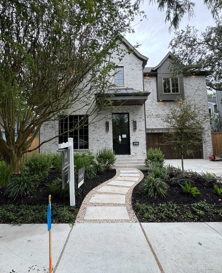 Modern two-story white house with a curved stone walkway and front landscaping