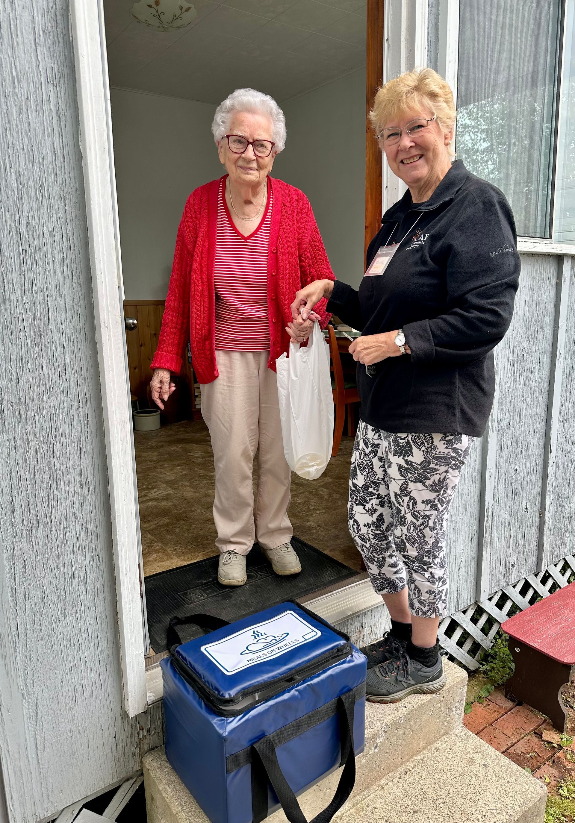 Two women are standing next to each other in front of a door.