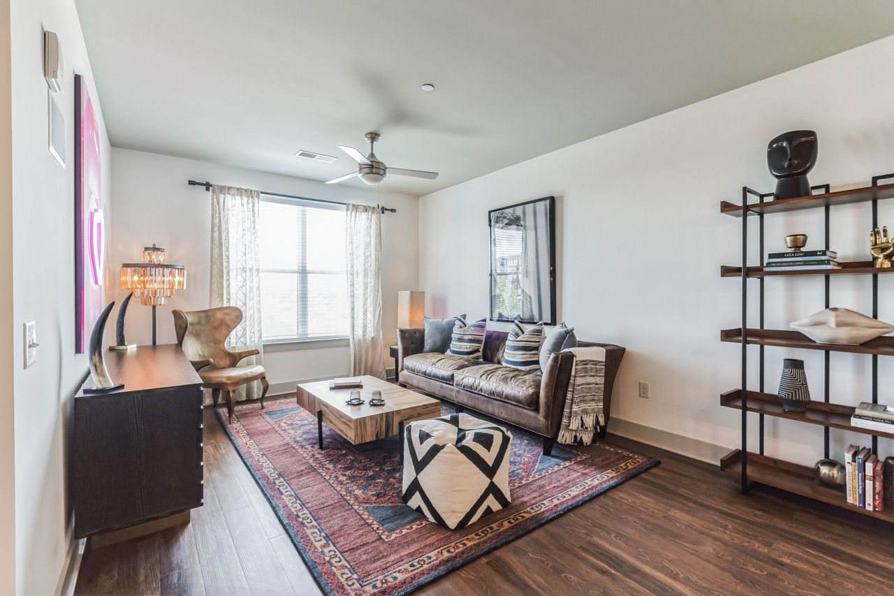 Living room of a modern apartment with a sofa, coffee table, rug, and shelving.