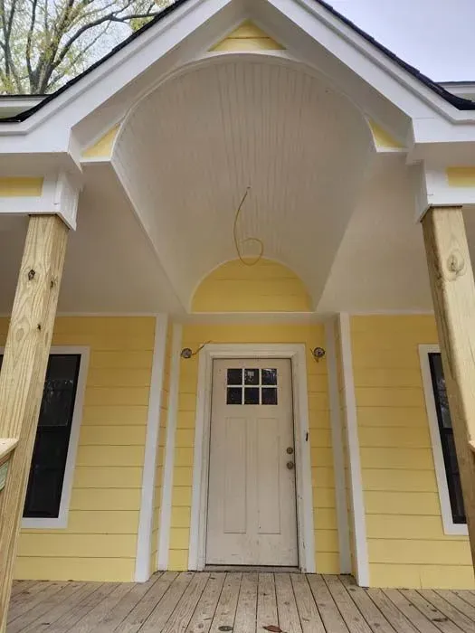 Yellow building with a white door and arched entryway.