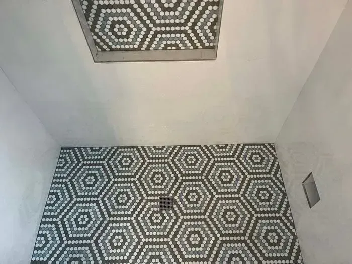 Bathroom with geometric hexagon tile floor and ceiling accents.