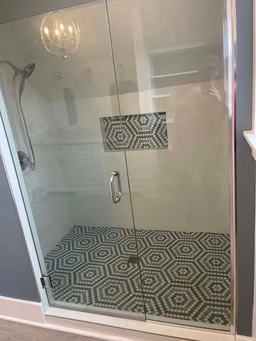 Glass shower with patterned floor and niche; white and grey tones.
