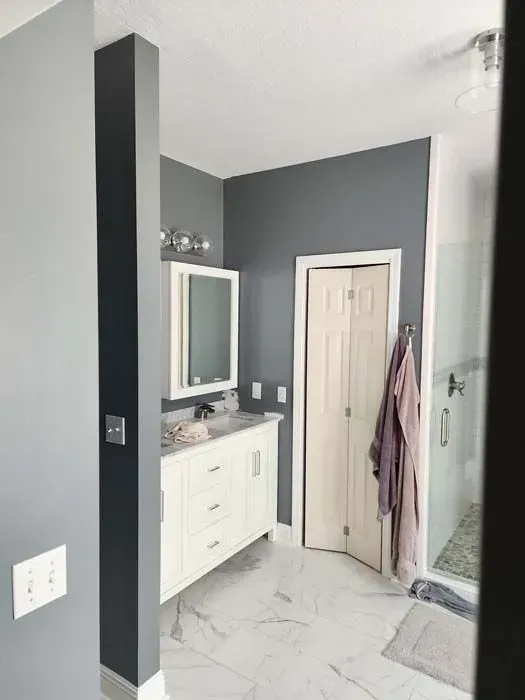 Gray and white bathroom with white vanity, gray walls, and closed door.