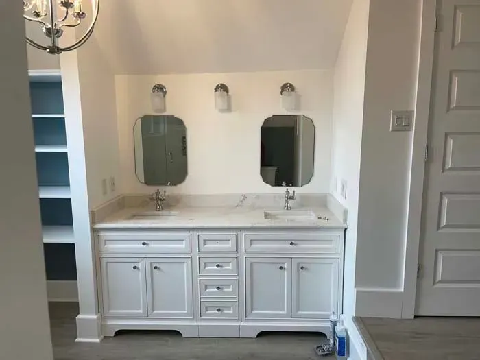 Bathroom with white vanity, two mirrors, and sconce lighting.
