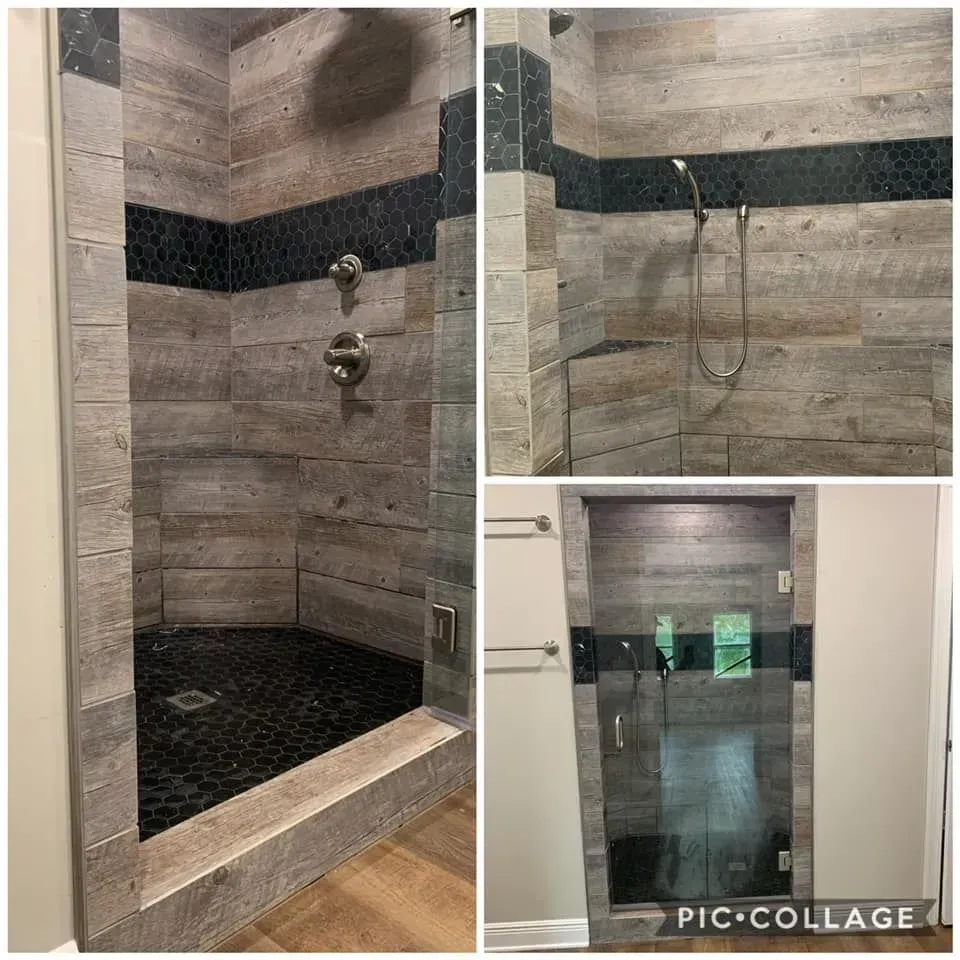 Shower with wood-look tile and black accents.  Glass door, gray and black stone floor.