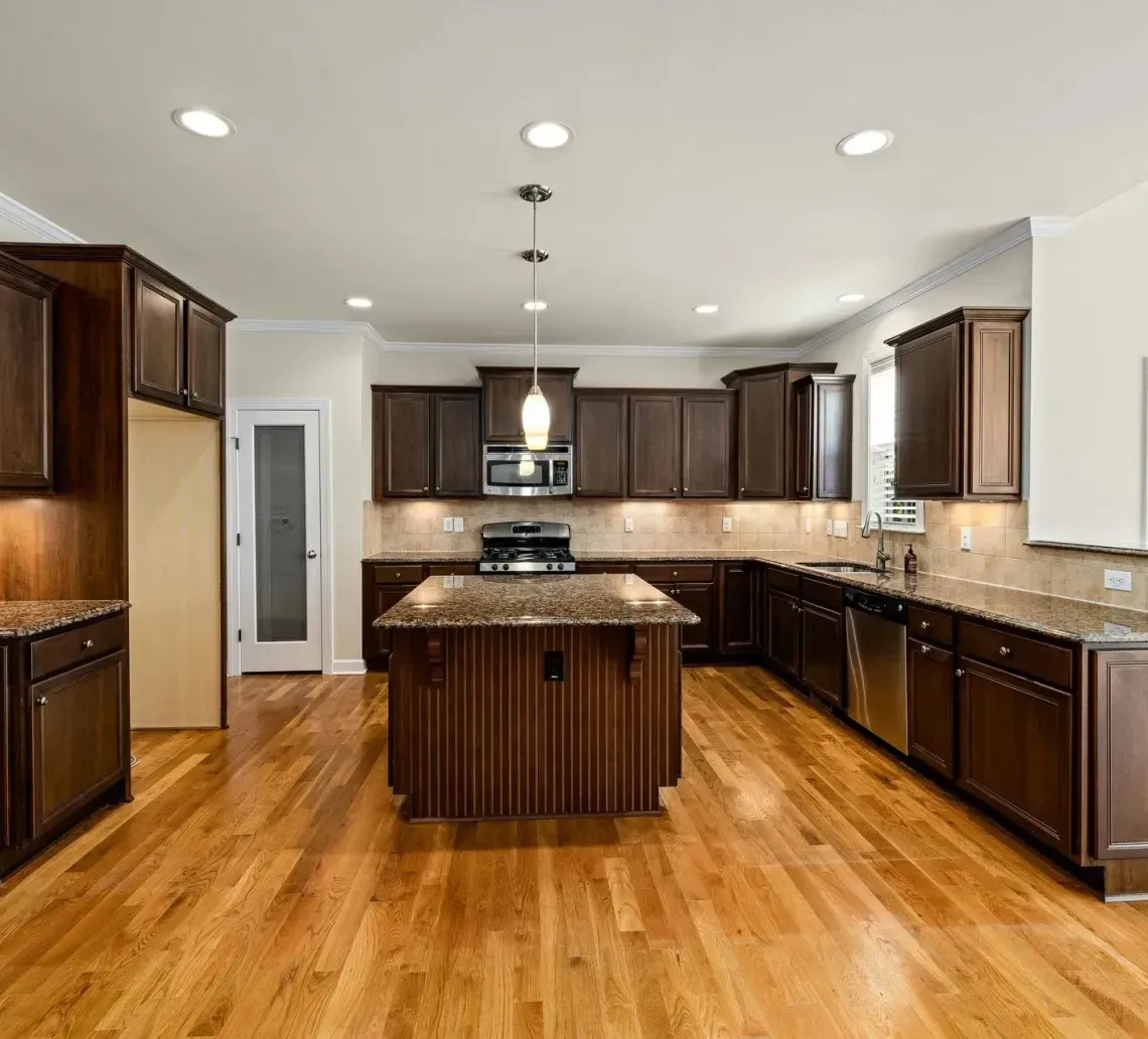 Spacious kitchen with dark wood cabinets, granite countertops, a central island, and hardwood floors.