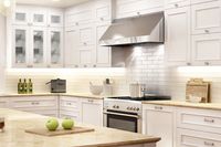 Modern white kitchen with shaker cabinets, stainless steel range hood, subway tile backsplash, and a granite island.