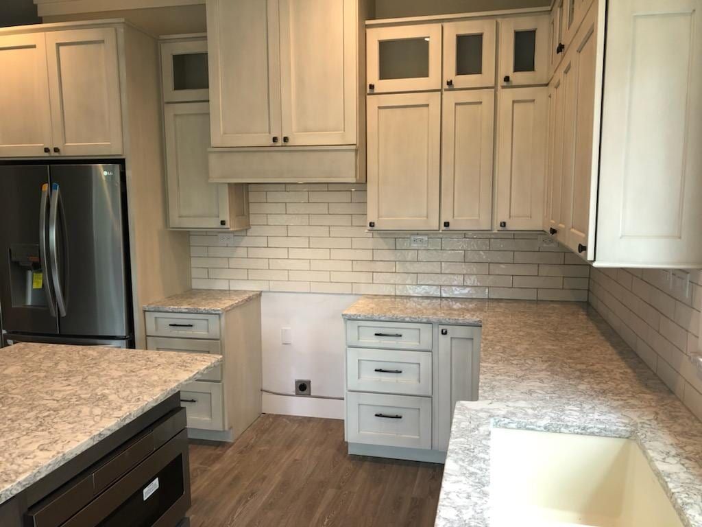 A kitchen with off-white cabinets, granite countertops, subway tile backsplash, and stainless steel appliances.