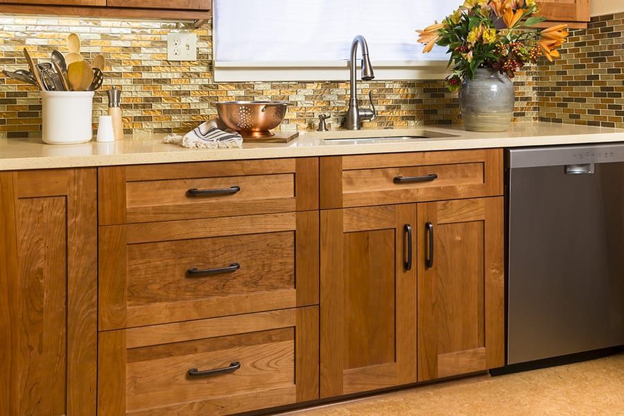 Kitchen countertop with wooden cabinets, a sink, a dish drying rack, and a floral arrangement.