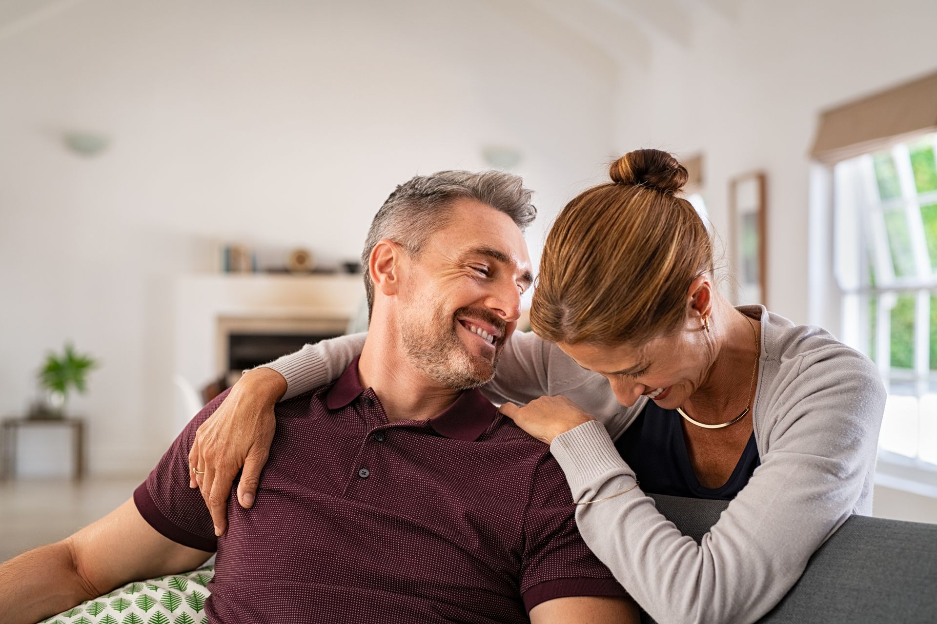 Smiling couple embracing on a couch indoors