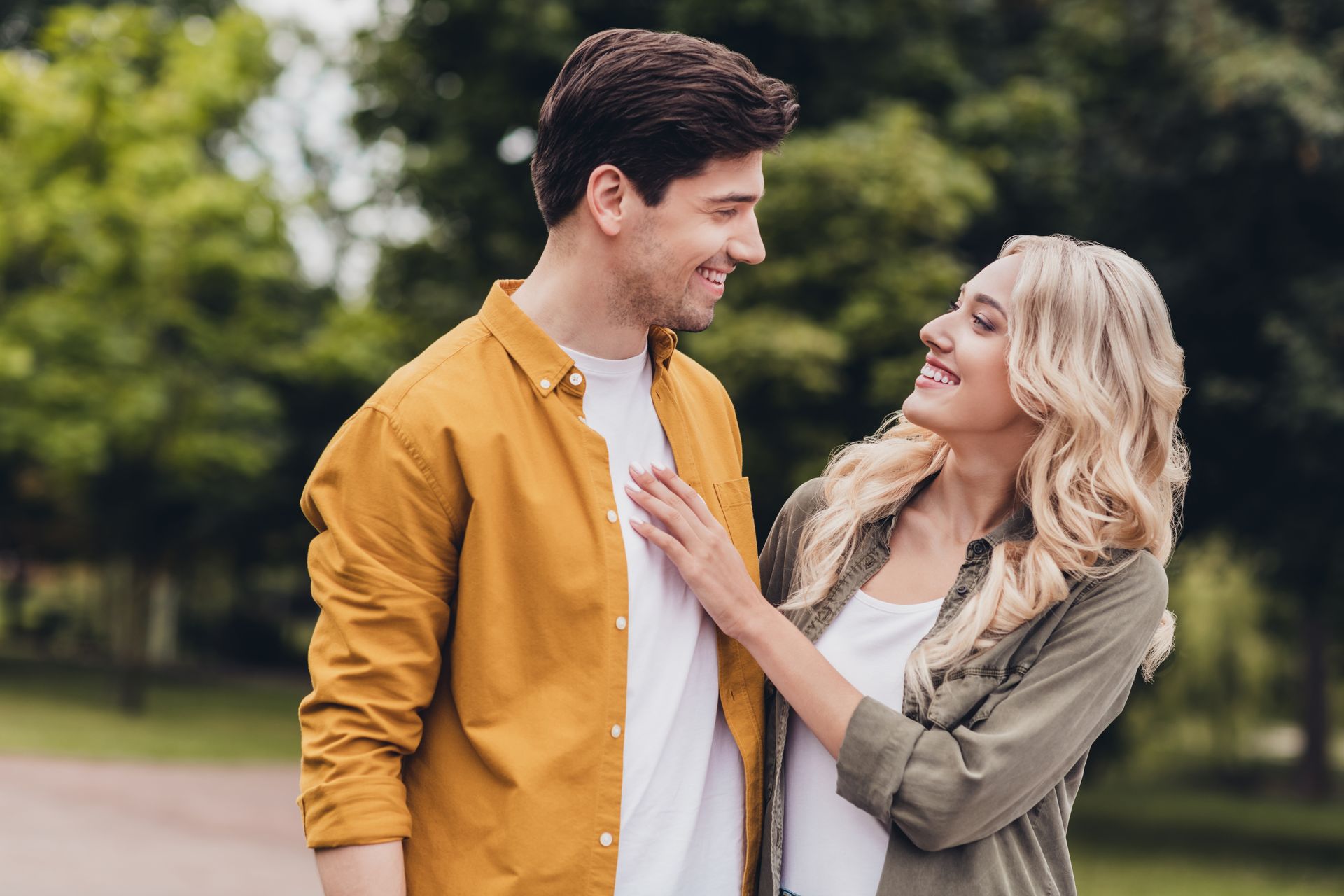 A smiling couple gazes at each other in a park