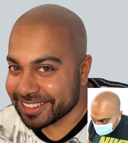 A man with a beard is smiling and wearing a mask