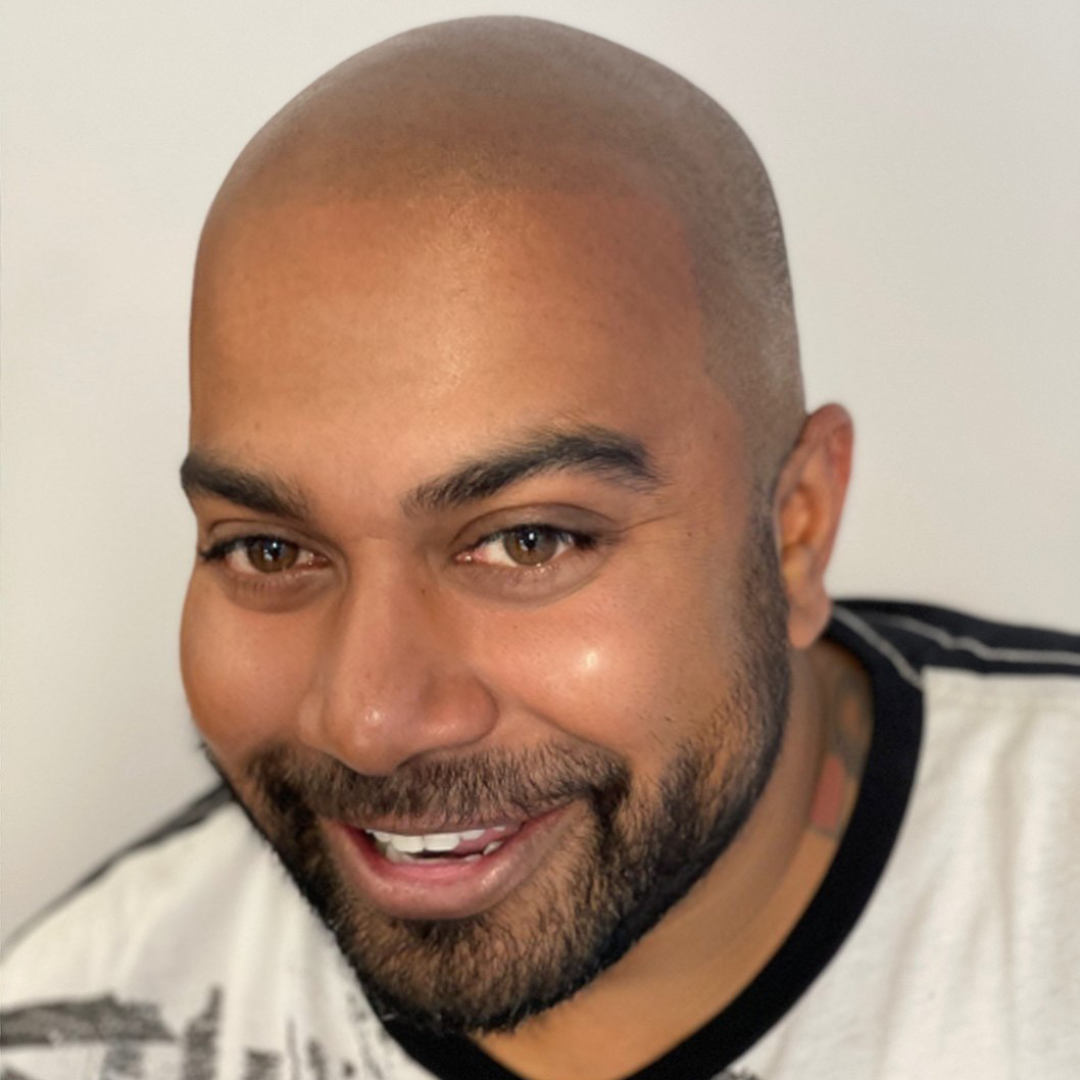 A bald man with a beard is smiling for the camera
