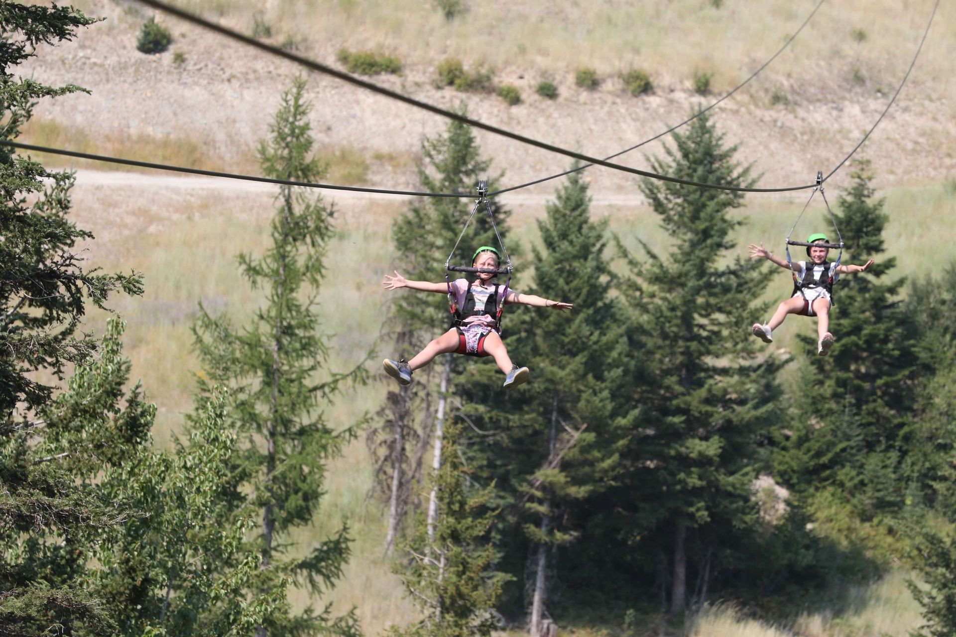 Two people are flying through the air on a zip line.