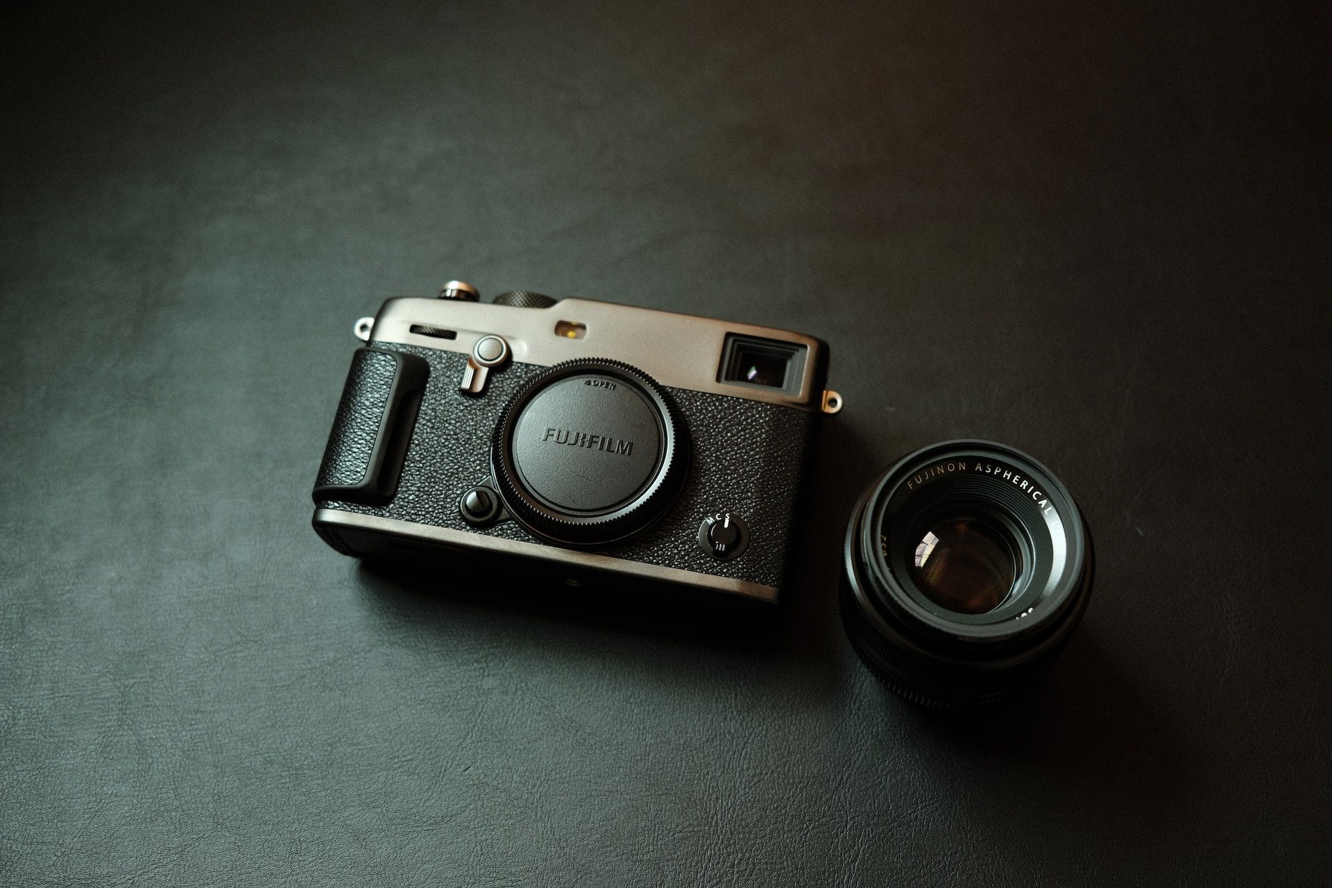 A Fujifilm X-PRO3 camera and lens sitting on a black surface.