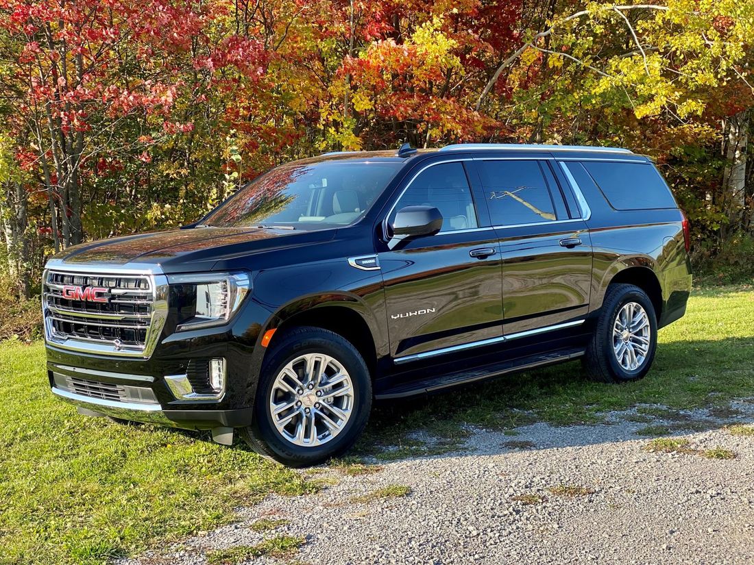 A black gmc yukon suv is parked in a grassy field.