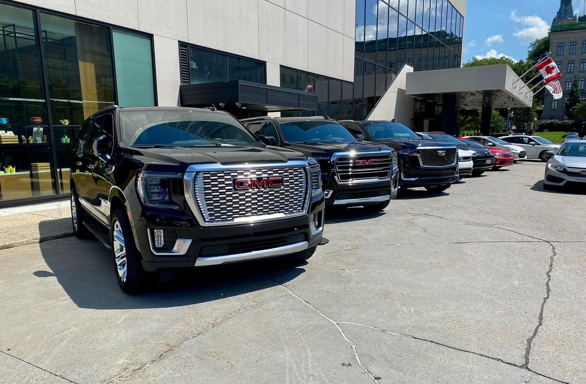 A row of gmc cars are parked in front of a building.