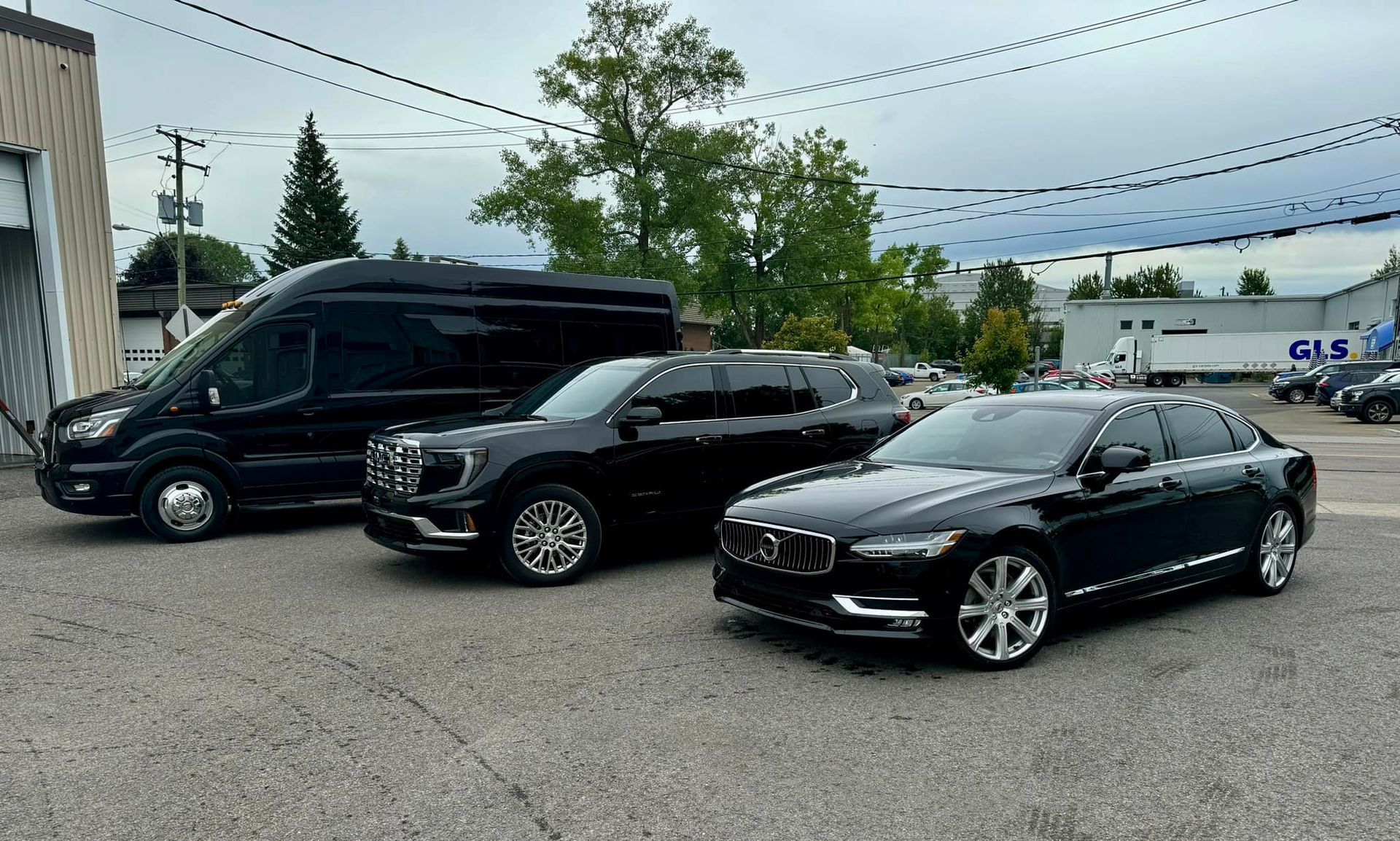 Three black cars are parked next to each other in a parking lot.