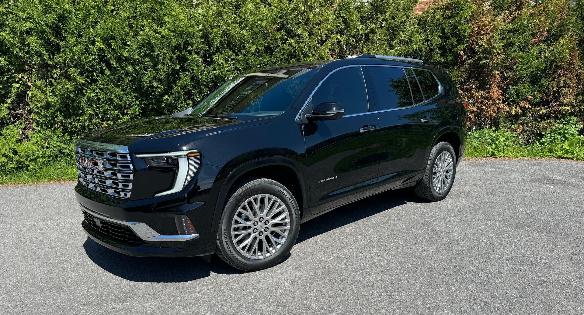 A black gmc acadia is parked on the side of the road.
