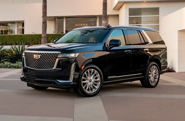 A black cadillac escalade is parked in front of a house.