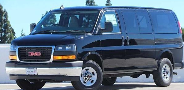 A black gmc van is parked on the side of the road.