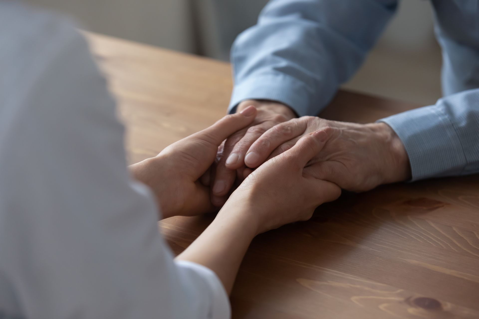 Una donna tiene la mano di un uomo mentre sono sedute a un tavolo.