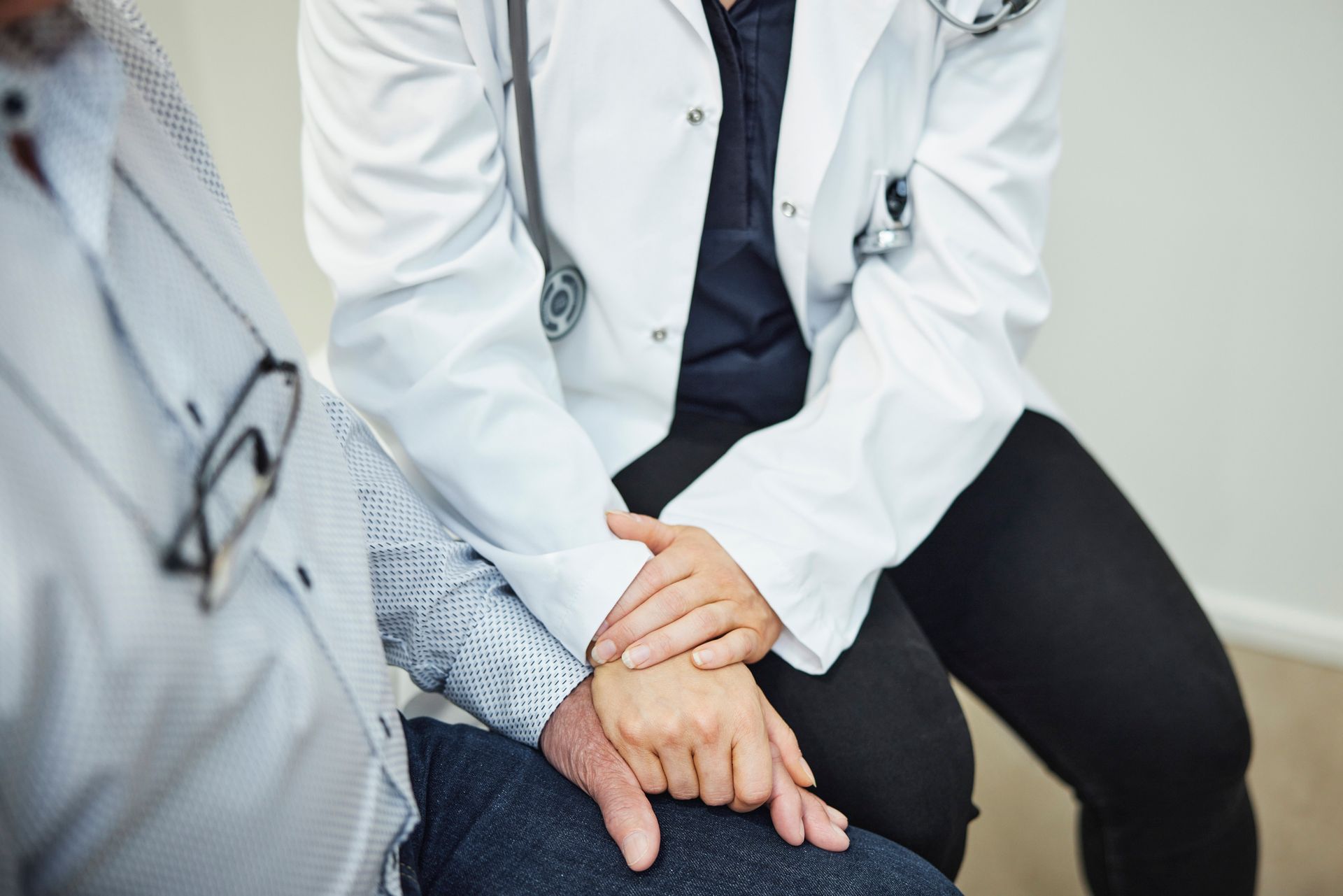 Un medico e un paziente sono seduti uno accanto all'altro e si tengono per mano durante una seduta di fisioterapia a domicilio a Torino