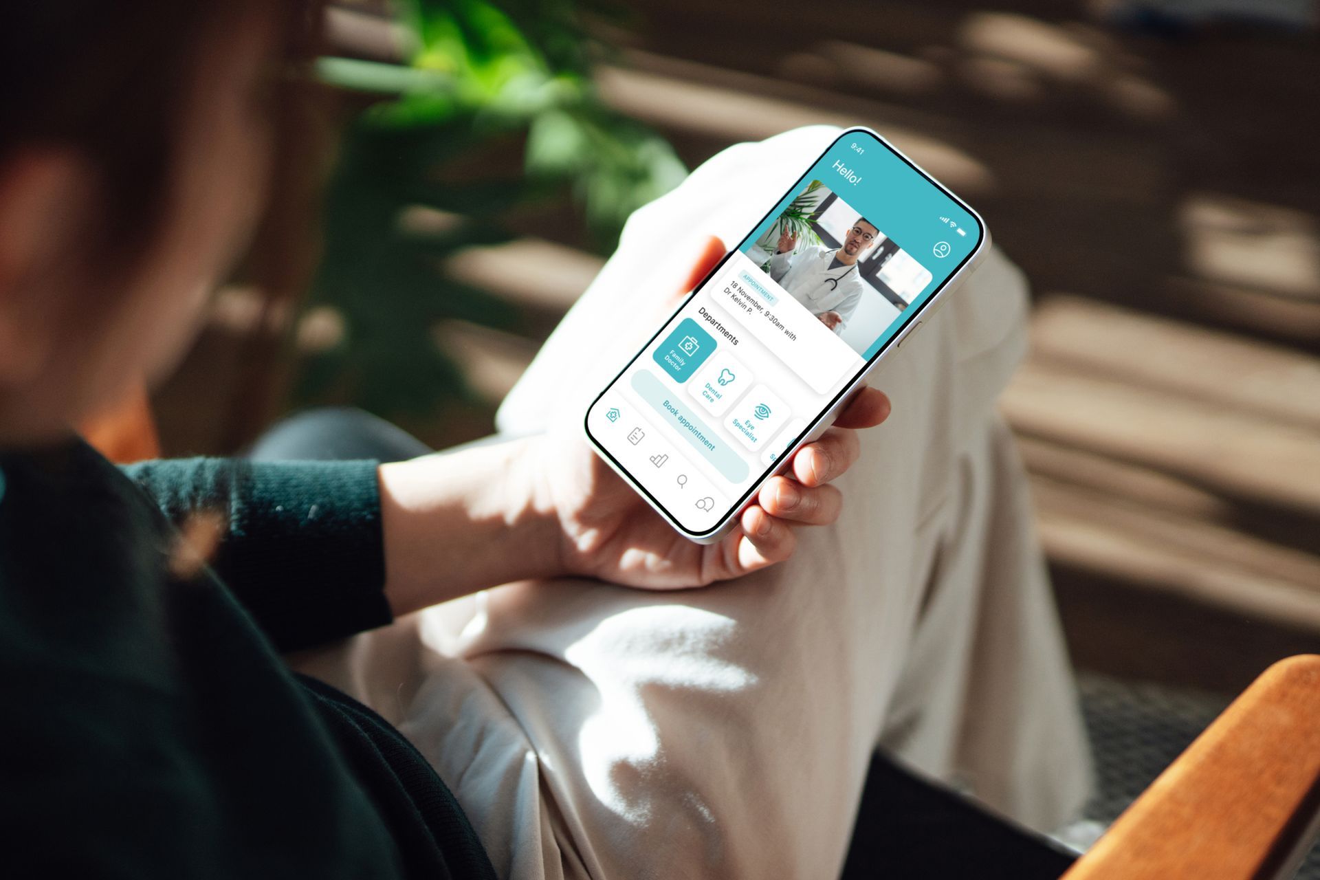 Una persona è seduta su una sedia e tiene in mano un telefono cellulare durante una seduta di fisioterapia domiciliare a Torino.