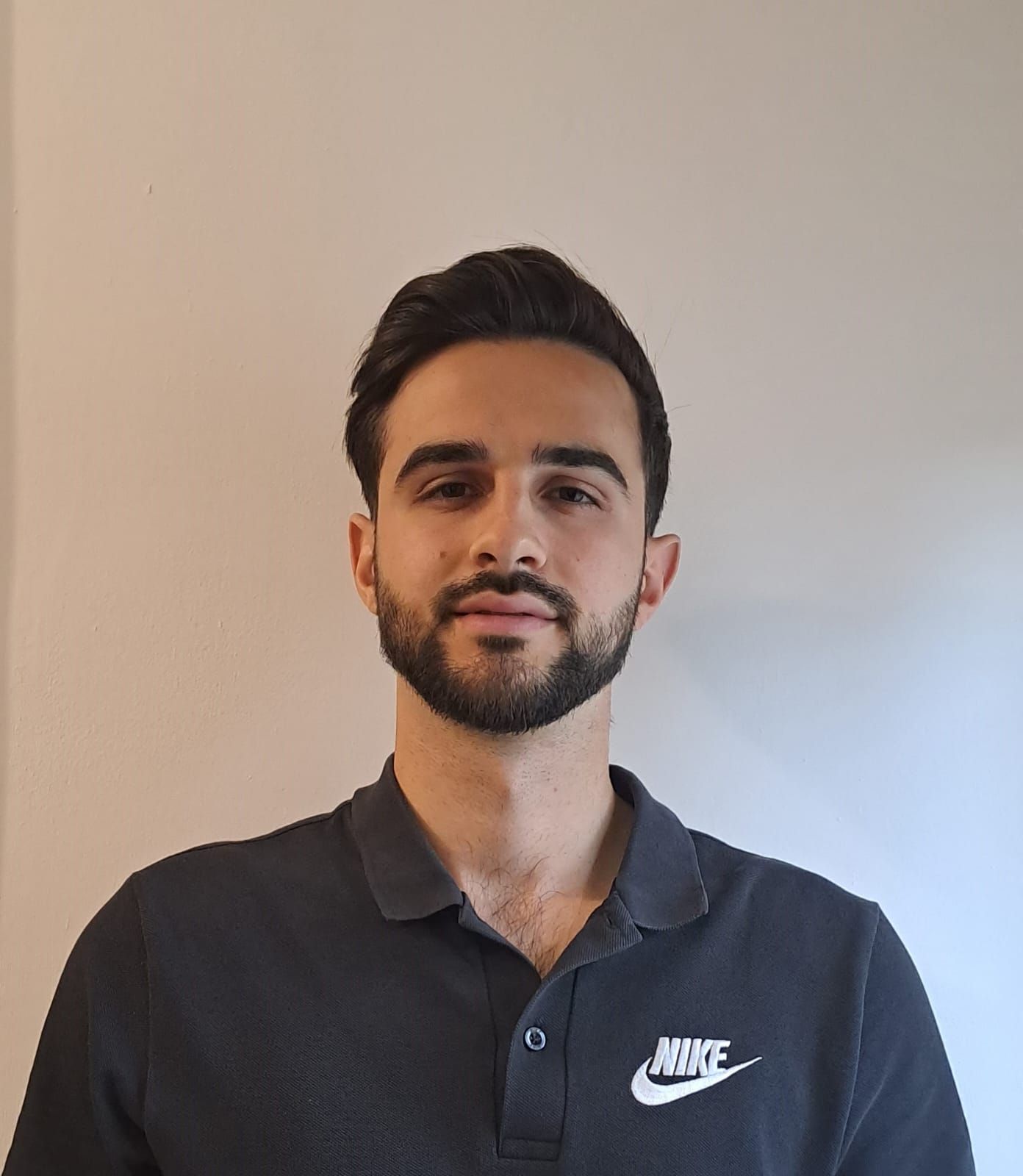 Un uomo con la barba che indossa una polo Nike nera