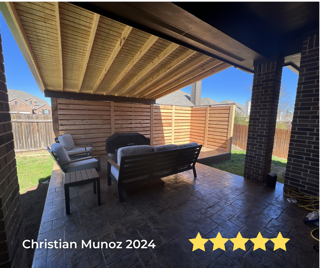 A patio with a couch and chairs under a wooden roof.