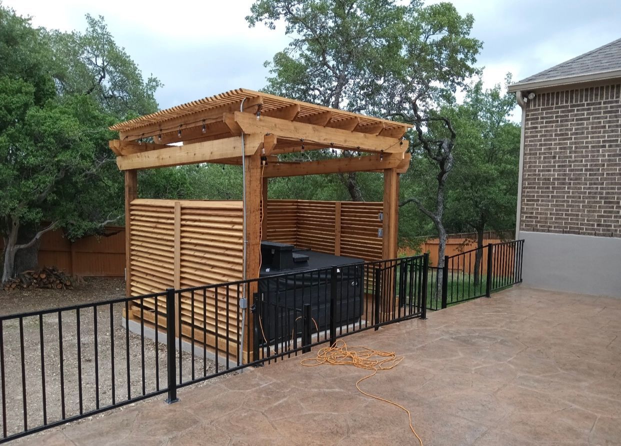 A wooden pergola is sitting in the backyard of a house.
