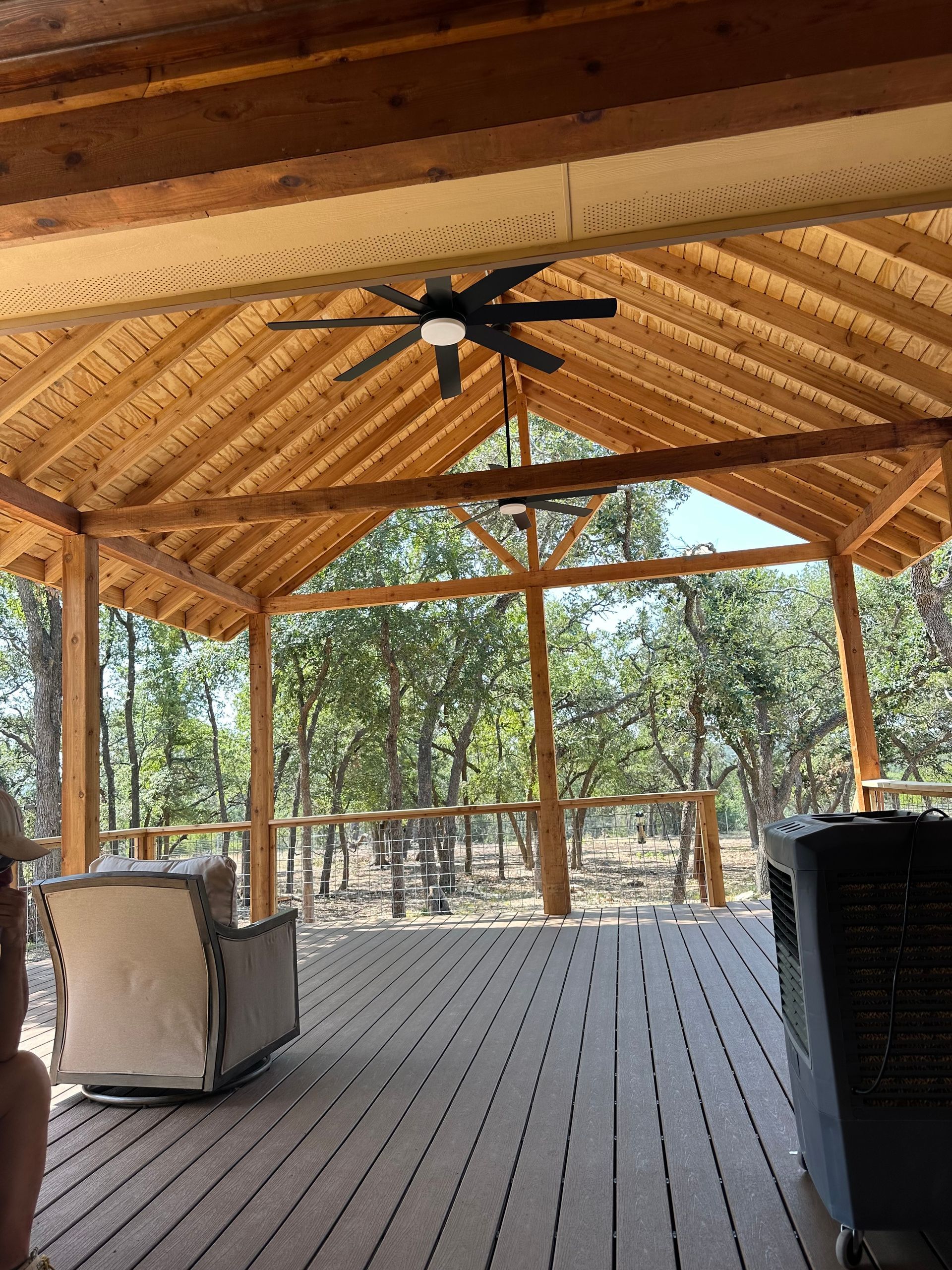 A ceiling fan is hanging from the roof of a wooden structure.