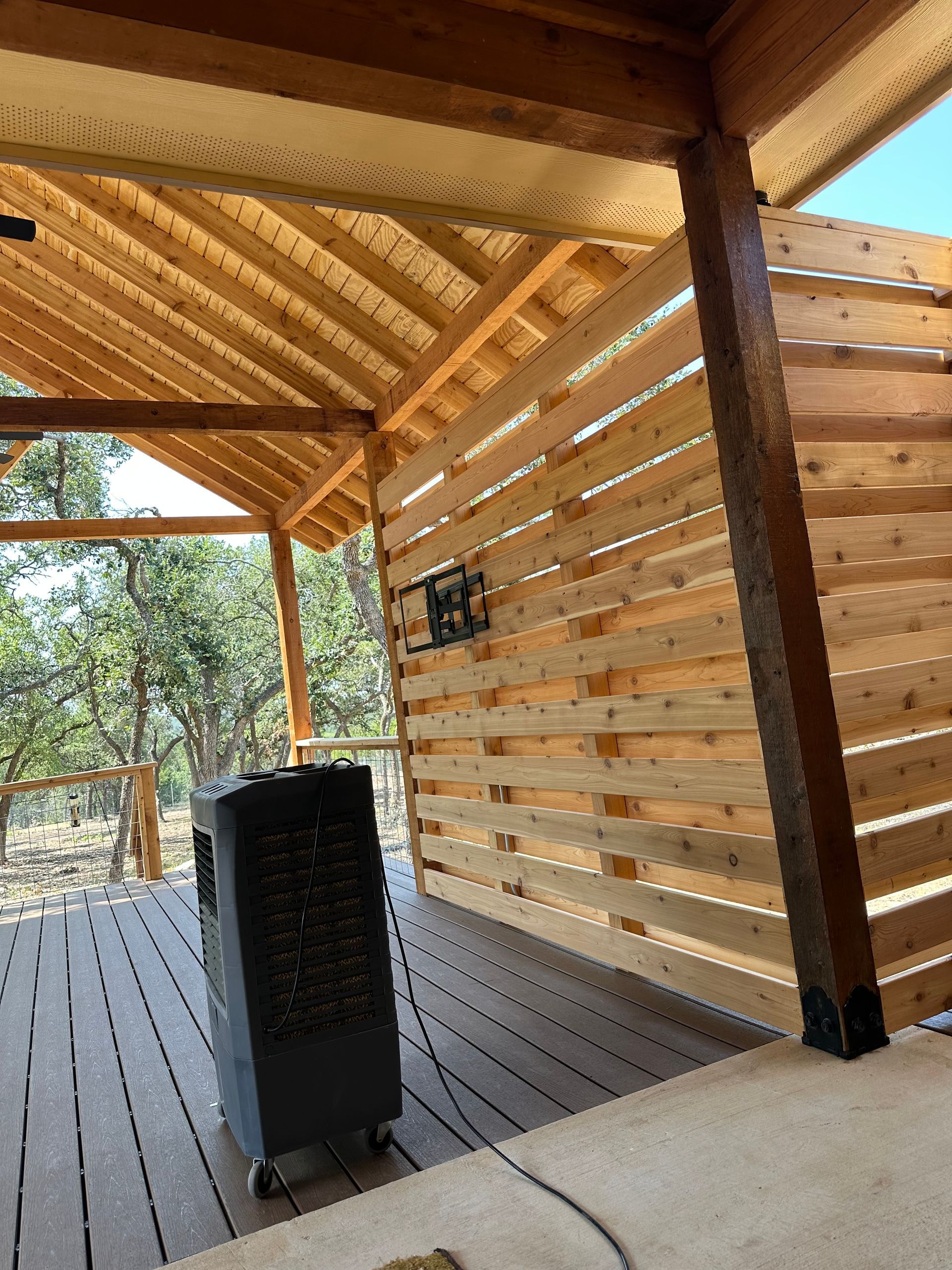 A wooden fence is surrounding a wooden deck with a ceiling fan.