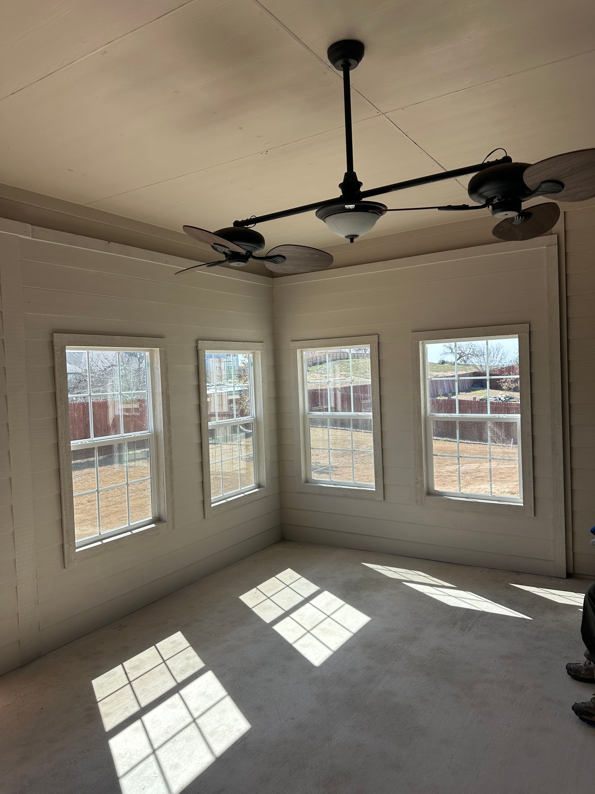 A room with a lot of windows and a ceiling fan.