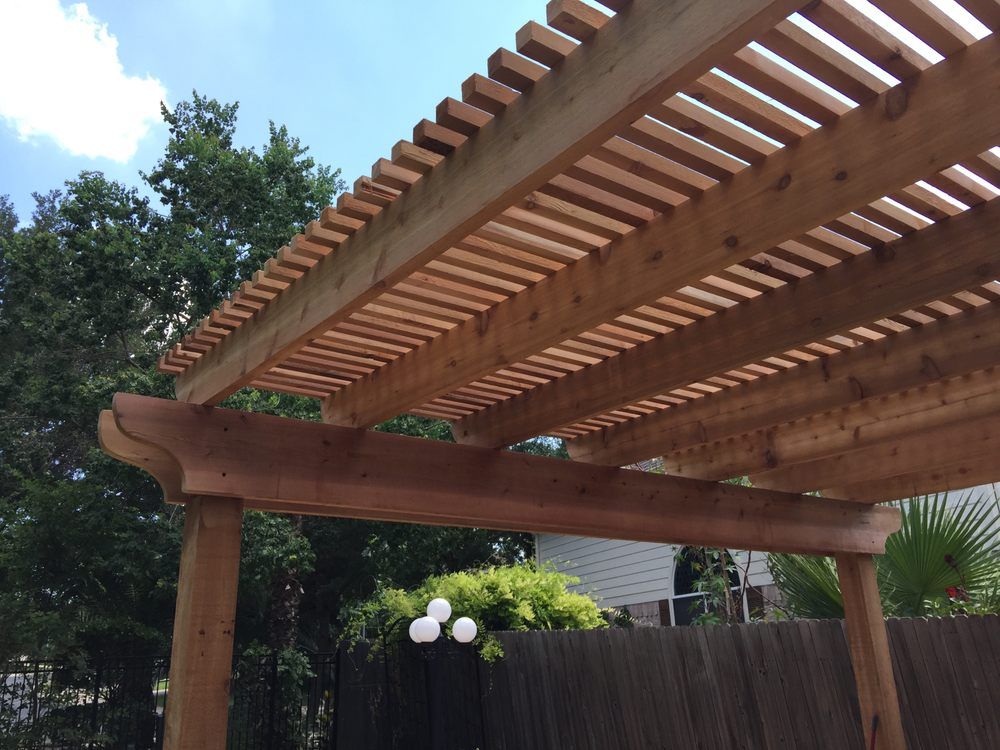 A wooden pergola with a fence in the background