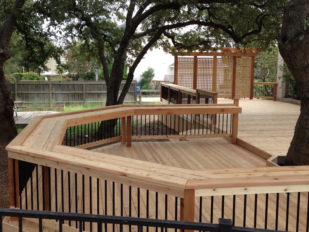 A wooden deck with a fence and trees in the background