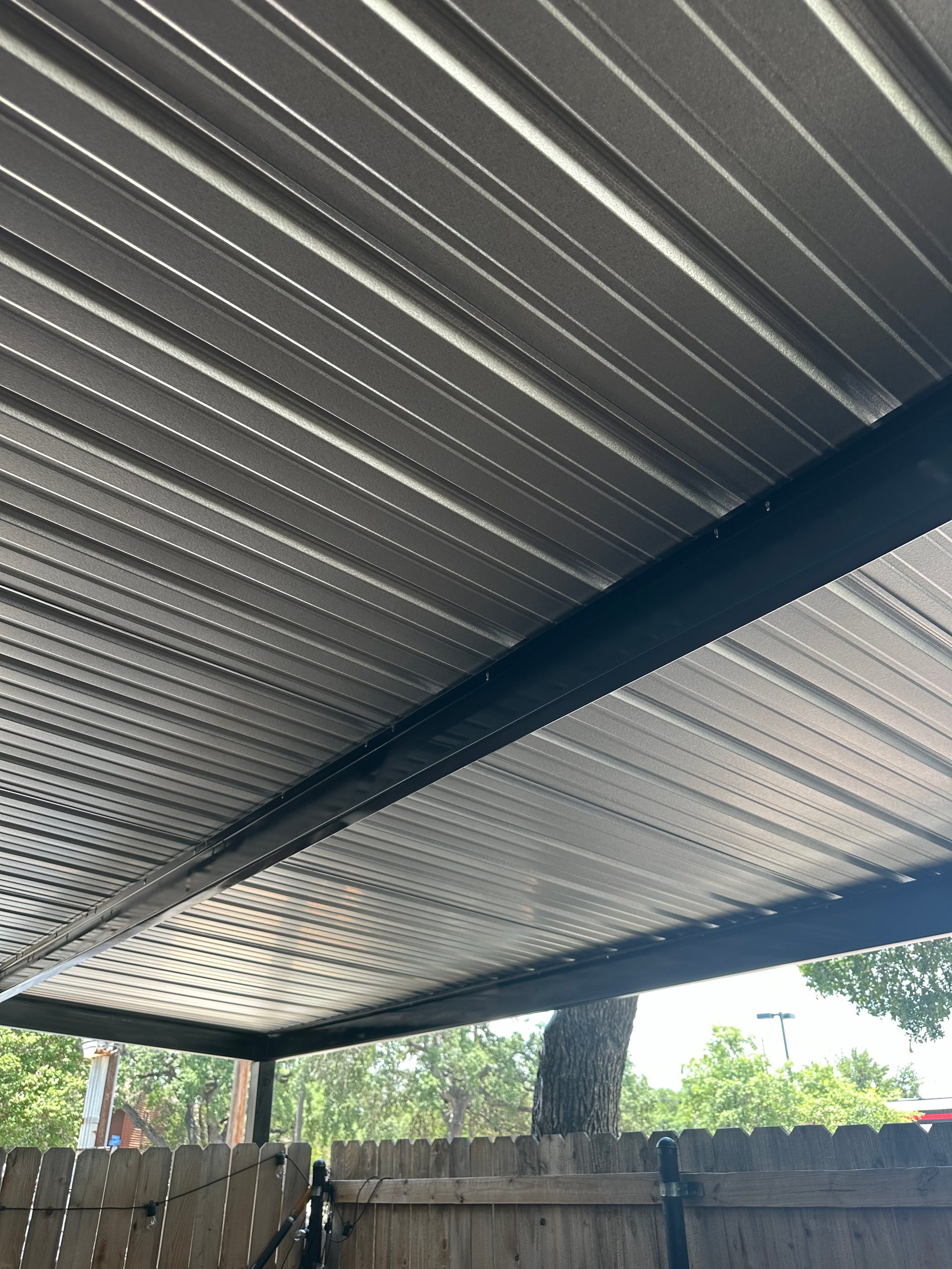 A metal roof with a wooden fence in the background.