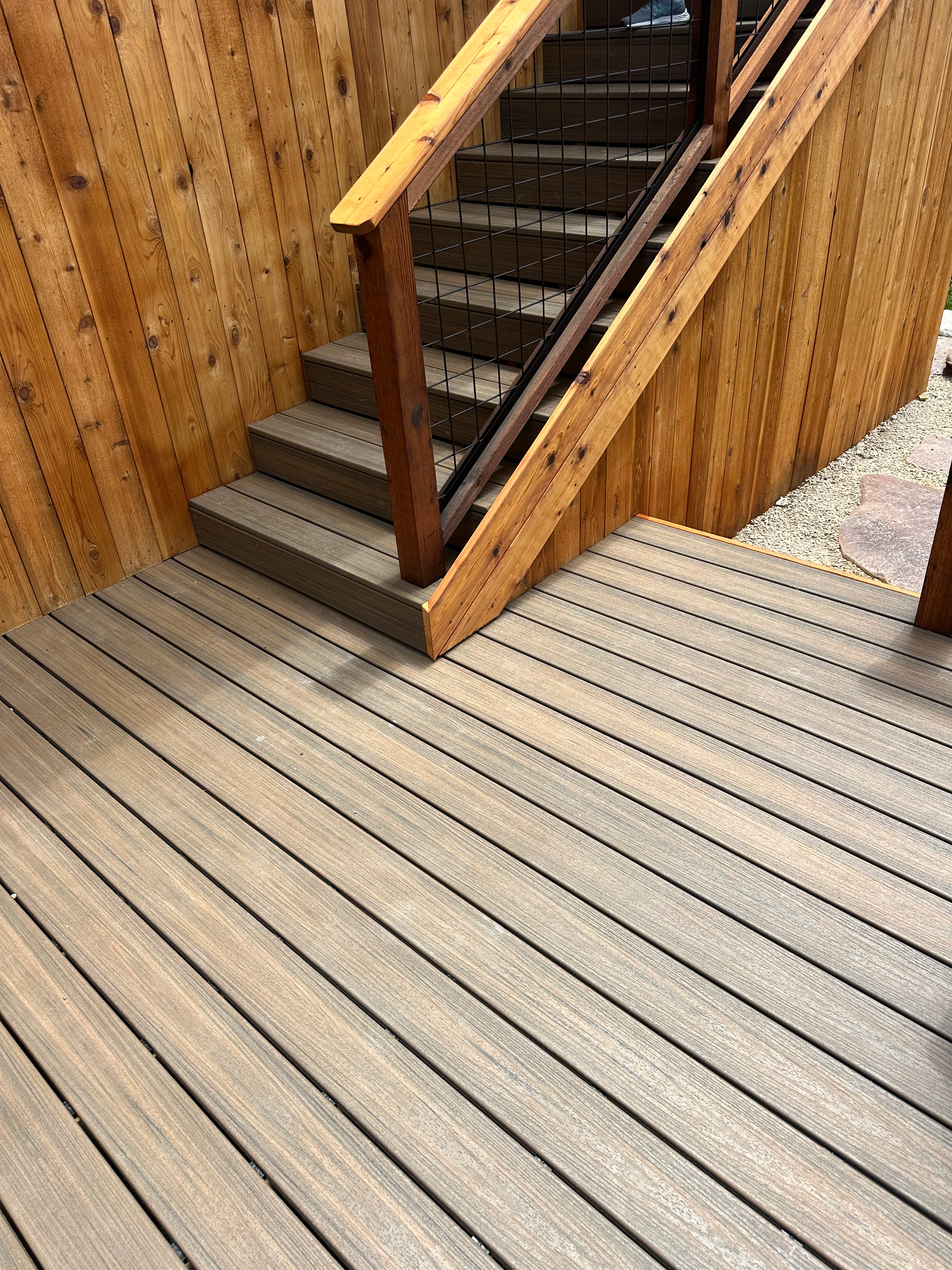 A wooden deck with stairs and a wooden railing.