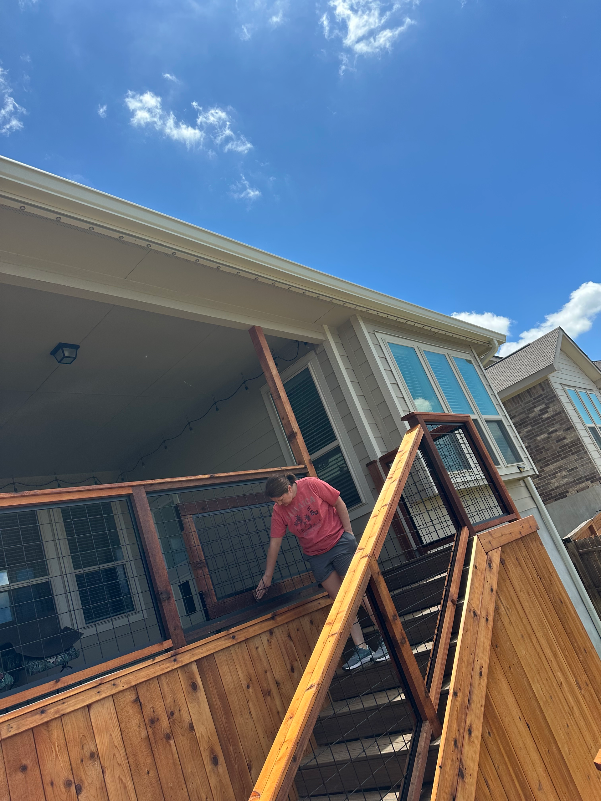 A man is standing on a wooden deck next to a house.