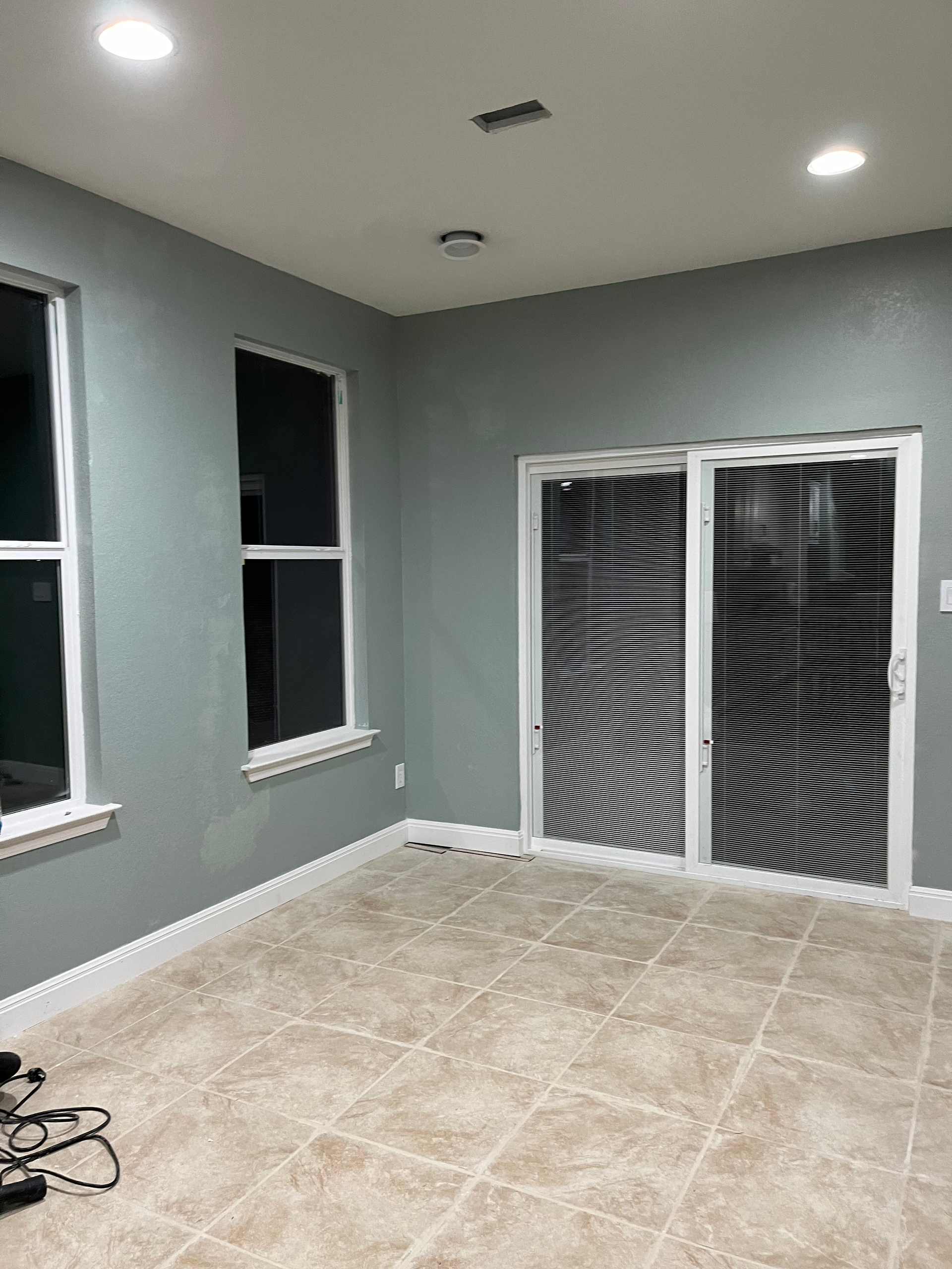 An empty room with a sliding glass door and two windows.