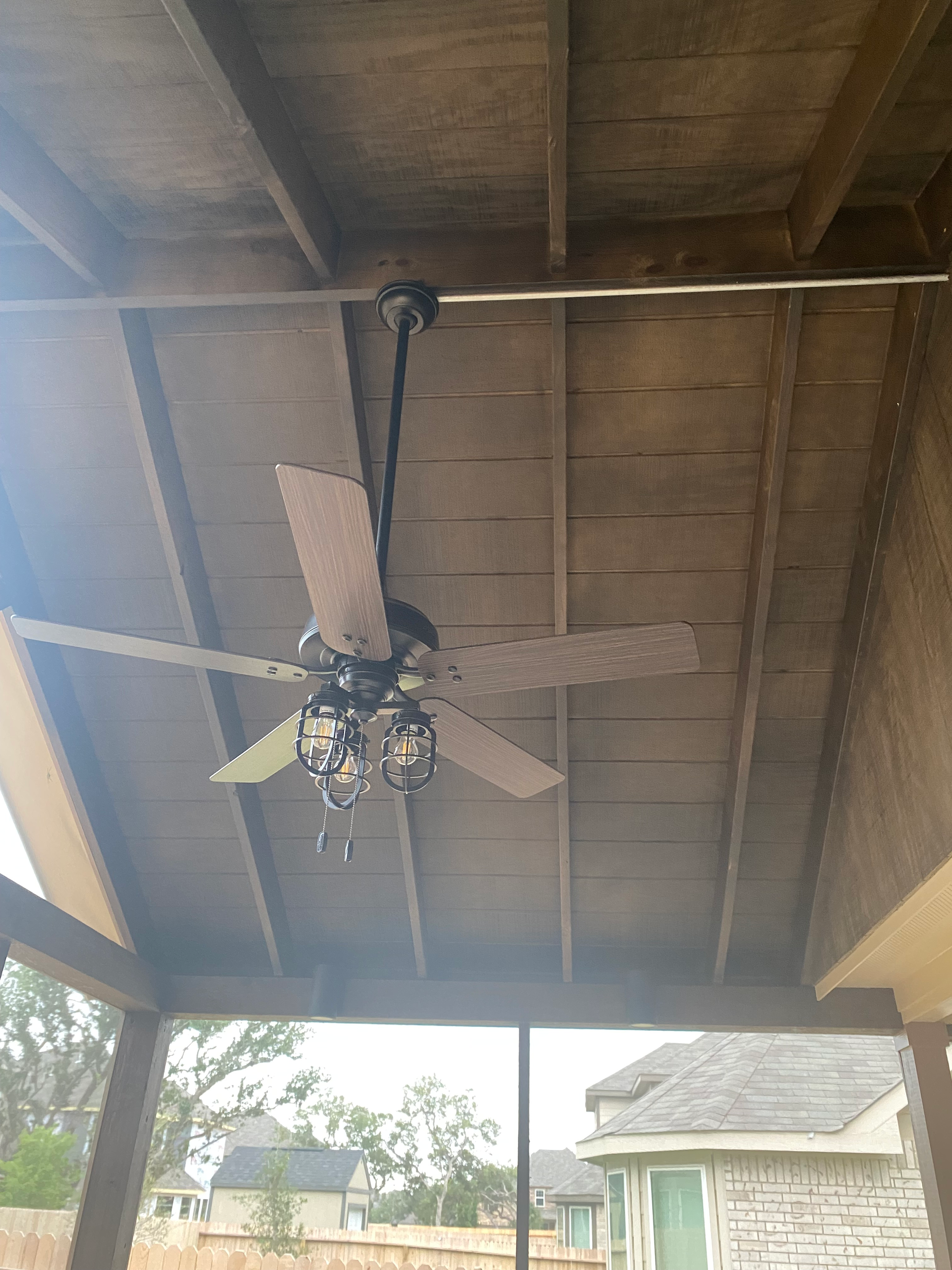 A ceiling fan is hanging from the ceiling of a porch.