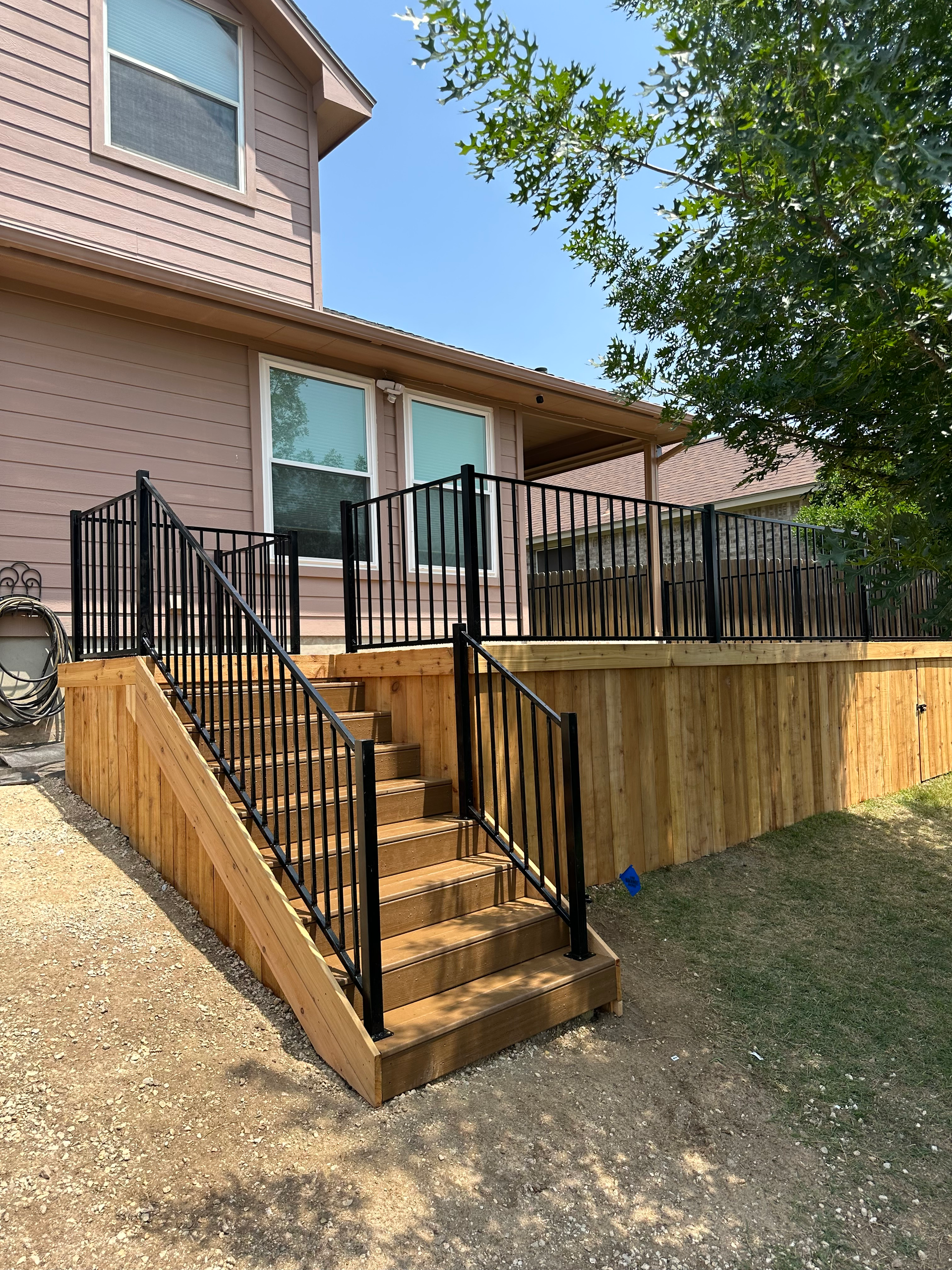 A wooden deck with stairs leading up to it next to a house.